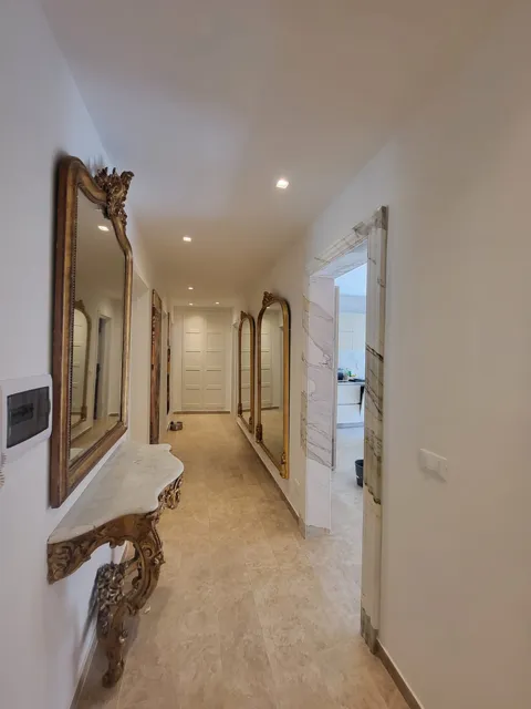 Corridoio con specchi e ingresso della cucina rivestito in marmo